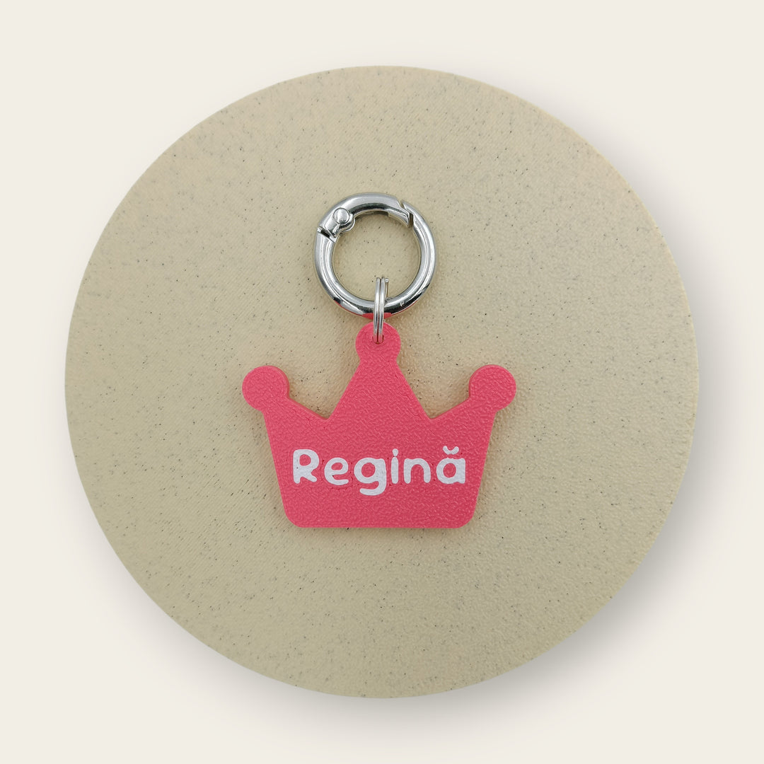 Medalion amuzant cu mesajul Regina, forma de coroana roz cu text alb, printat 3D din PLA - Ubba.