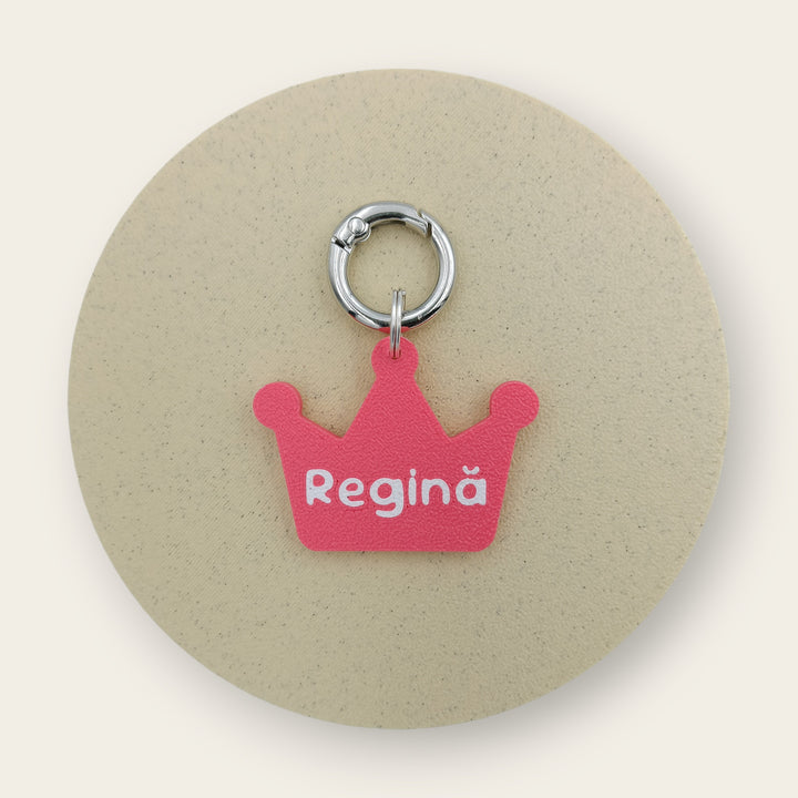 Medalion amuzant cu mesajul Regina, forma de coroana roz cu text alb, printat 3D din PLA - Ubba.